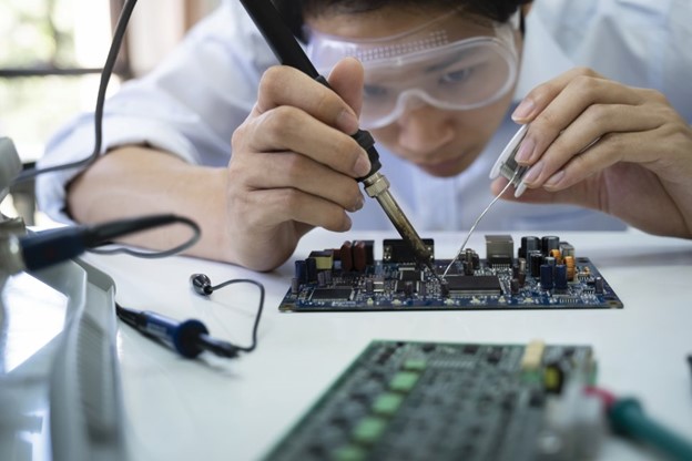 A worker hand soldering a circuit board